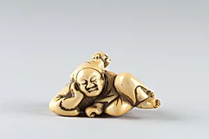 Netsuke of a Man Sleeping while Monkey Steals Contents of Basket
