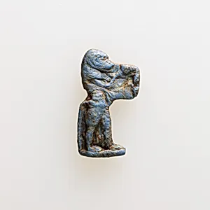 Amulet of a baboon holding an unrecognizable object