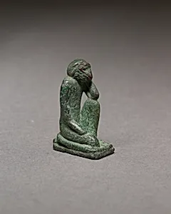 Monkey kneeling and resting its head in a hand