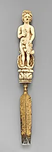 Paper knife with carved handle of nude with sun in hair standing in a half shell holding a swag by Unknown Artist
