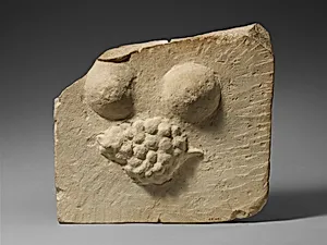 Limestone plaque with breasts and a bunch of grapes in relief