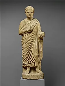 Limestone statue of a wreathed boy holding a ball or piece of fruit