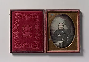 [Man Wearing Coat and Gloves, Holding Hat, Seated in Front of Painted Outdoor Backdrop] by Samuel Broadbent Jr.