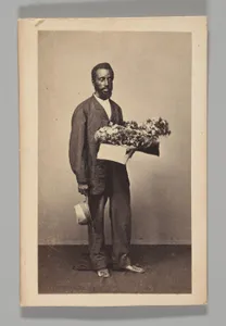 [Studio Portrait: Male Street Vendor Holding Box of Flowers, Brazil]