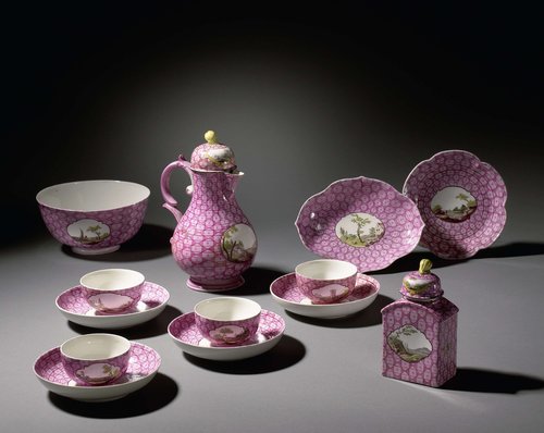 Delen van een koffie- en theeservies, met een veelkleurig landschap in een medaillon uitgespaard in een geometrisch patroon