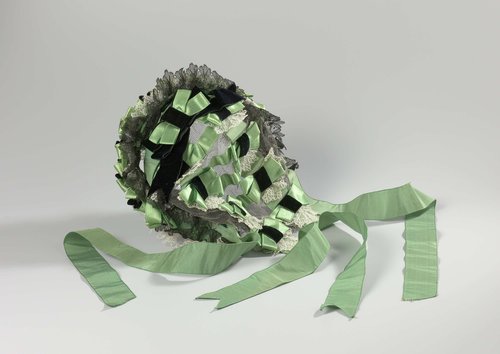 Bonnet-coiffure van groen satijn, zijden lint, bandfluweel en kant op een zwart tulen ondergrond genaaid by anonymous