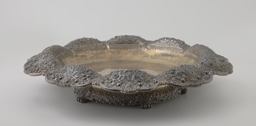 Schaal van zilver, met geplooide, gelobde rand, geheel bewerkt met bloemen en rocailles.