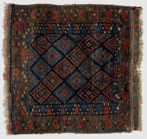 Kussenvoorblad met blauw rasterdessin, gezigzagde driehoeken, rozetten en margrieten.