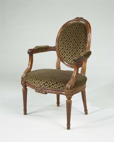 Armstoel van mahoniehout, met conische, gecanneleerde poten en op voorzitregel versierd met een strik. Bekleed met groene velours met patroon van rozetten. Bekleding niet origineel. by anonymous