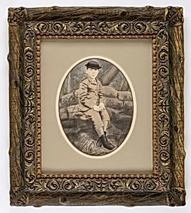 Boy Wearing Brimmed Hat Seated before Painted Rustic Setting by Unidentified