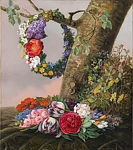 En buket blomster ved foden af et træ. På en gren hænger en blomsterkrans