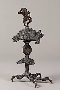 Olielampe (?). Pan-figur dansende på en skilpadde, der hviler på en baluster, som bæres af en rovfugleklo by Ubekendt