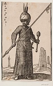 Stående soldat, skildret frontalt; i højre hånd en lanse med en vimpel på spidsen, i venstre en kølle og på hovedet en turban med to fjer; i baggrunden et "fyrtårn" samt to obelisk-lignende bygninger by Melchior Lorck
